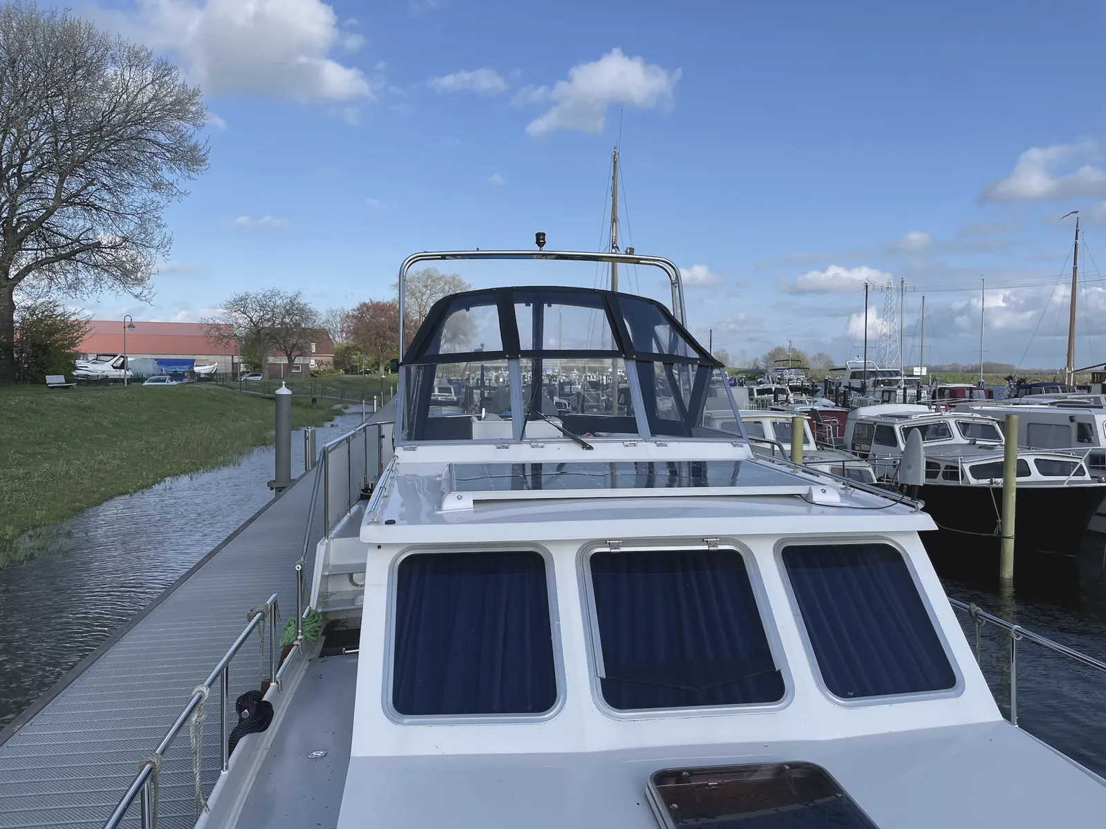 Motorkruiser met sprayhood op maat en gepolijst RVS-frame aan de steiger bij Kortenhoef